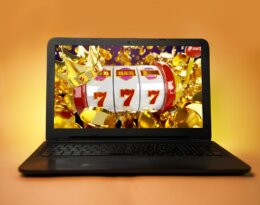 Laptop,On,Orange,Yellow,Background,,Casino,Winnings,Concept,,777,And
